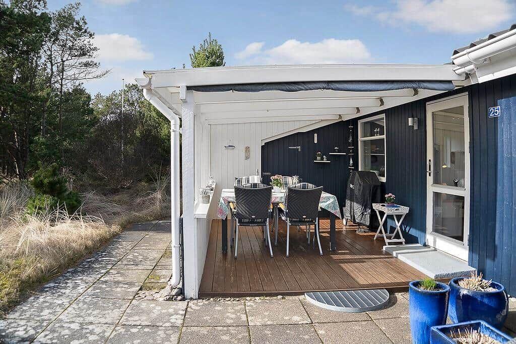 Terrasse mit Tisch, Stühlen und Pavillon neben blauem Haus mit Zugang zur Wohnung.