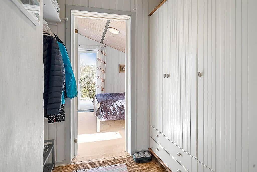 Schlafzimmer mit Bett und Fenster. Kleiderständer und Schrank sind sichtbar.