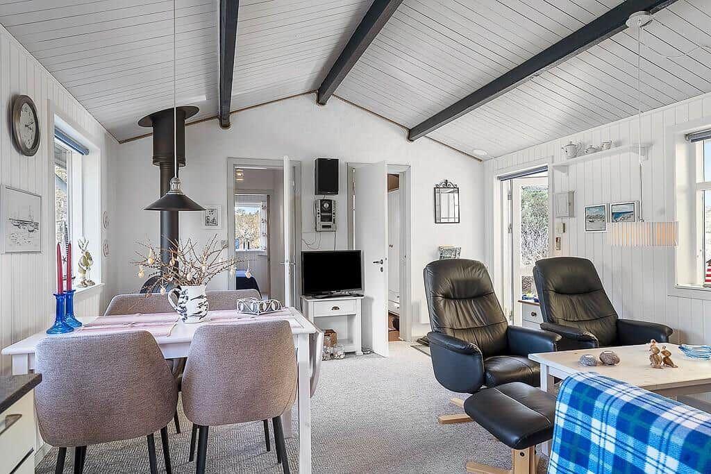 Wohn- und Essbereich mit Tisch, Stühlen, Fernseher und zwei Ledersesseln.