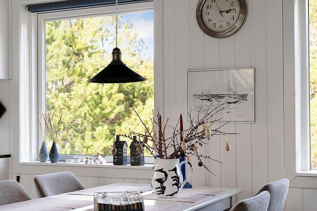 Esstisch mit Vase, Fenster und Wanduhr