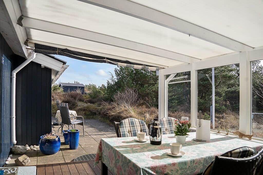 Terrasse mit Tisch, Stühlen und Blick auf Grünflächen.