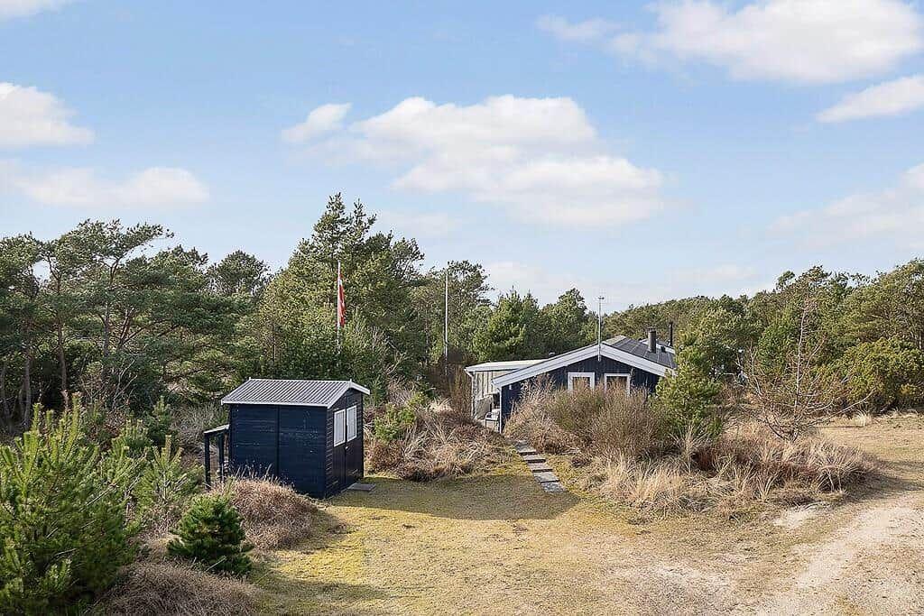 Zwei Holzhäuser in einer natürlichen Umgebung mit Bäumen und Gras.
