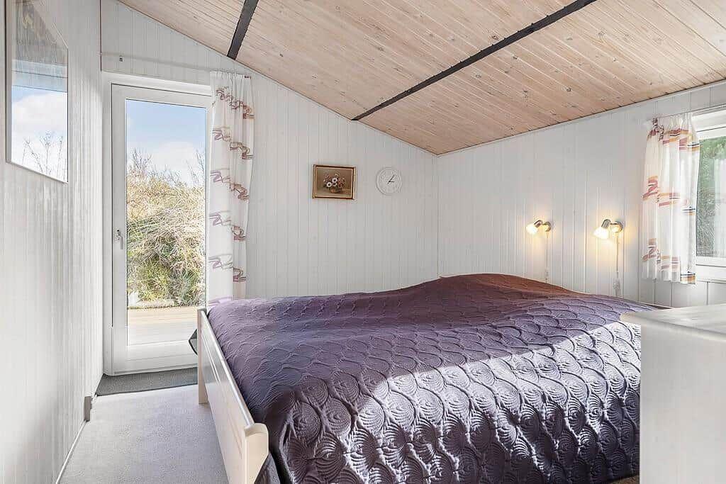Schlafzimmer mit Doppelbett, Holzdecke und Fenster zur Aussicht.