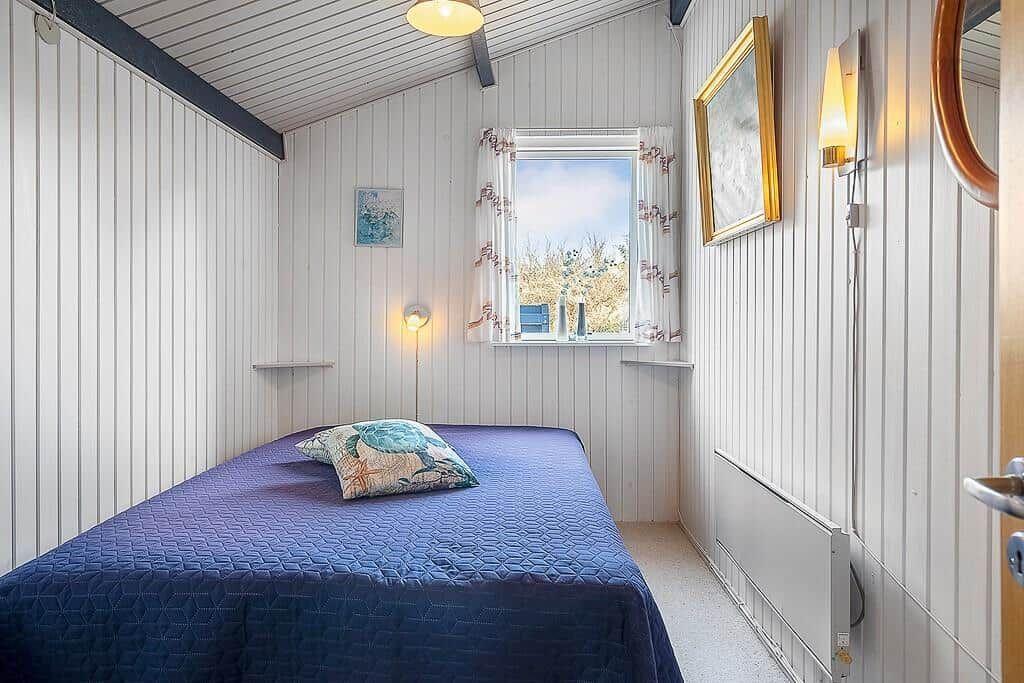 Ein Schlafzimmer mit Bett, Fenster und Wandbehang.