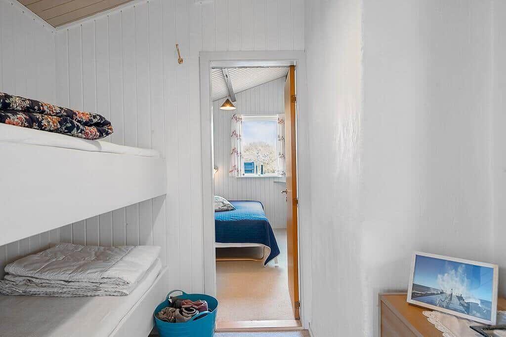 Zimmer mit Doppelstockbetten und Blick auf ein weiteres Schlafzimmer mit Bett.