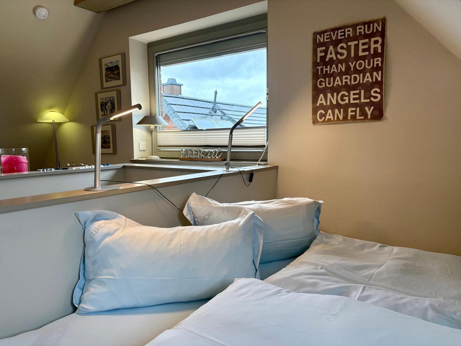 Bedroom with bed, window, and wall sign. A sign is on the windowsill.