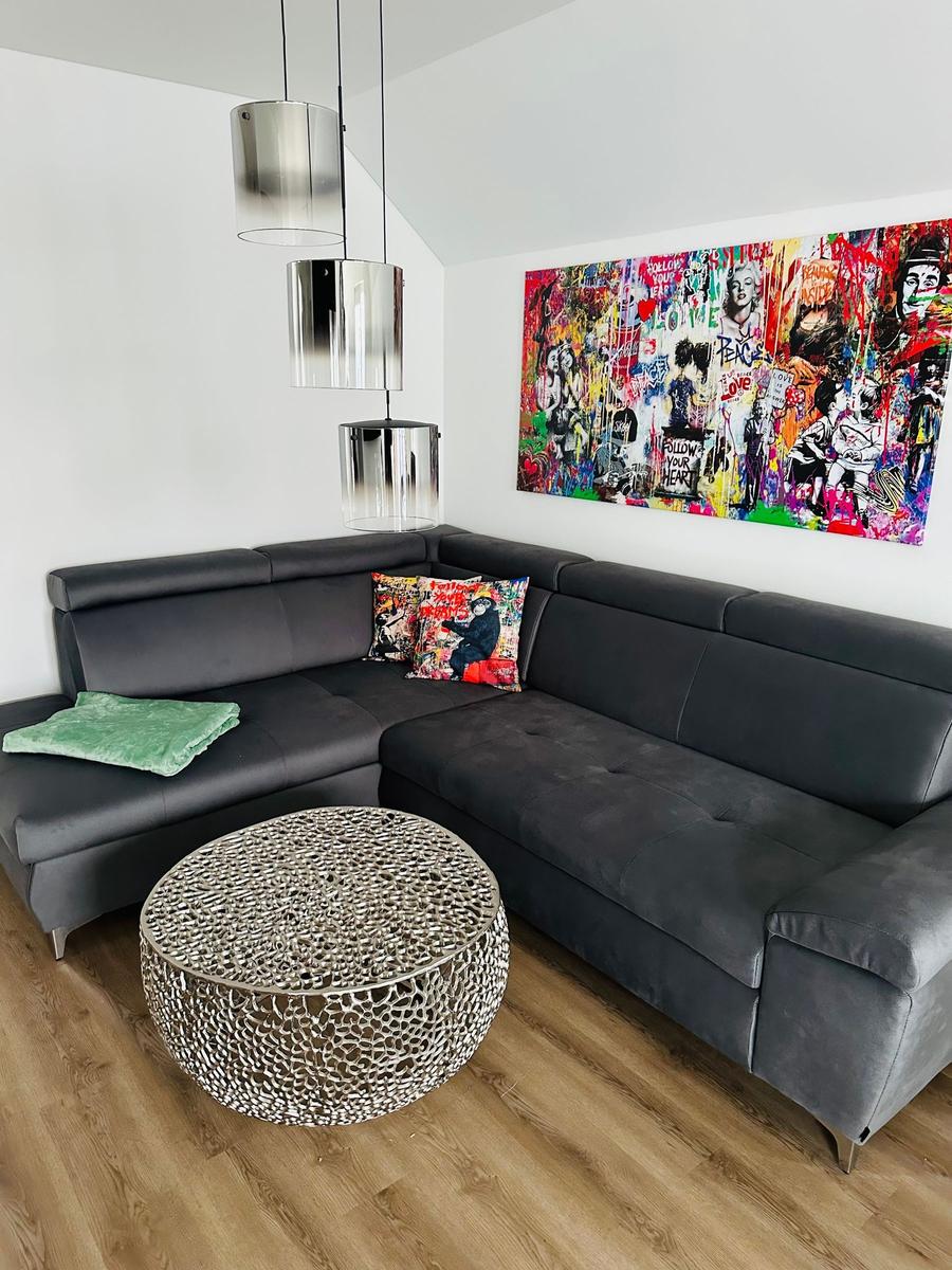 Schwarzer Ecksofa mit Kissen und runden Tisch vor Wandbild