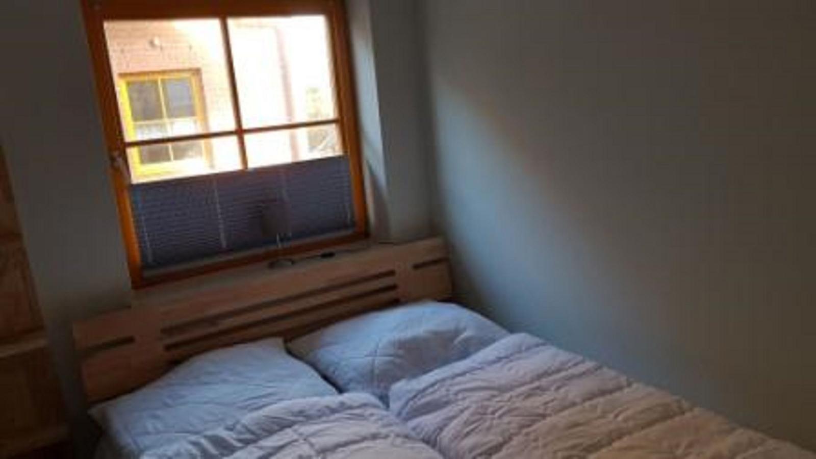 Ein Schlafzimmer mit einem Bett und einem Fenster mit Jalousie.