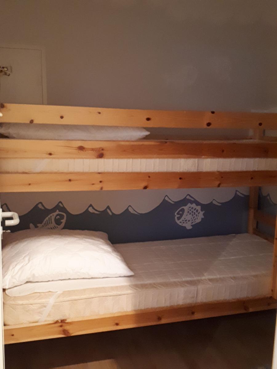 Doppelstockbett mit Matratzen und Kissen. Wandbild mit Fischen und Wellen.