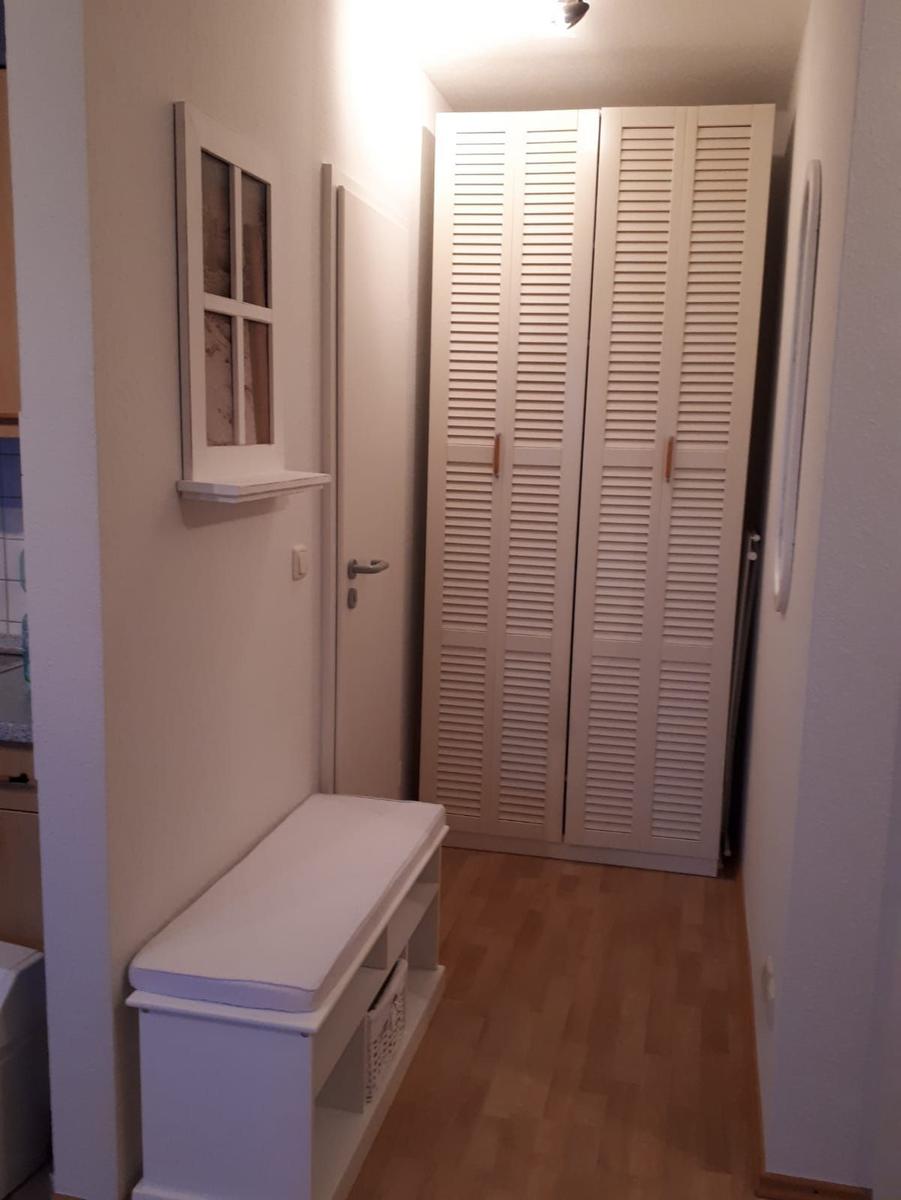 Flur mit Kleiderschrank, Sitzbank und Wandregal.