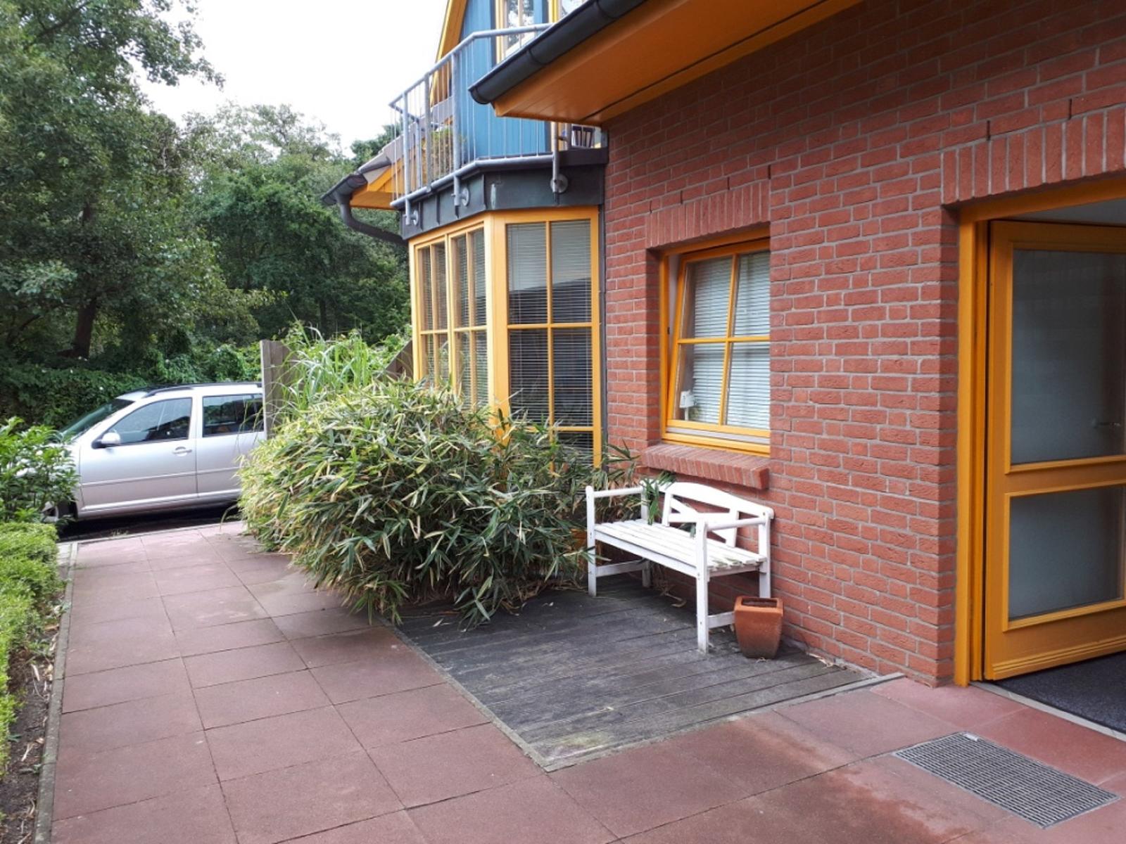 Haus mit rotem Backstein, gelben Fenstern und weißer Bank vor der Tür.