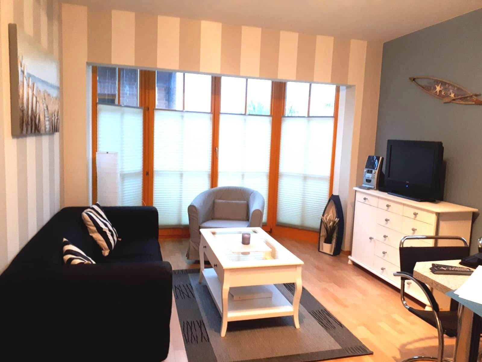 Wohnzimmer mit Sofa, Sessel, Couchtisch und Fernseher.