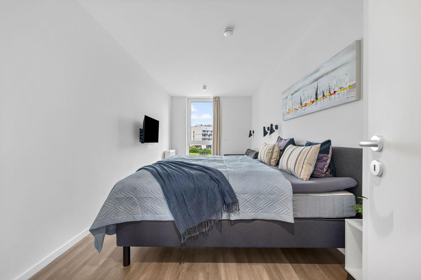 Schlafzimmer mit Bett, Wandbild, Fenster und TV.