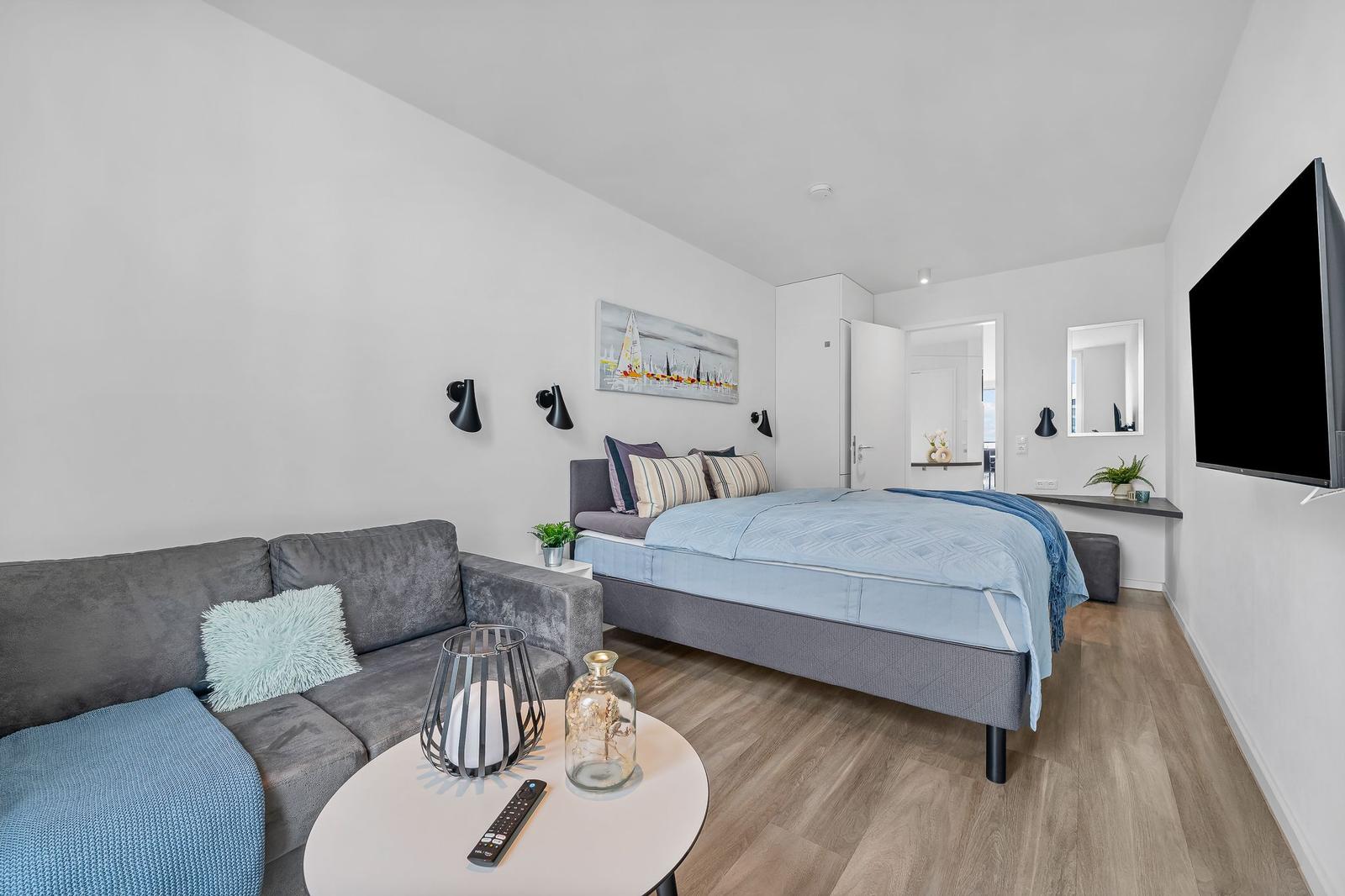 Ein Schlafzimmer mit Sofa, Bett und Fernseher an der Wand.