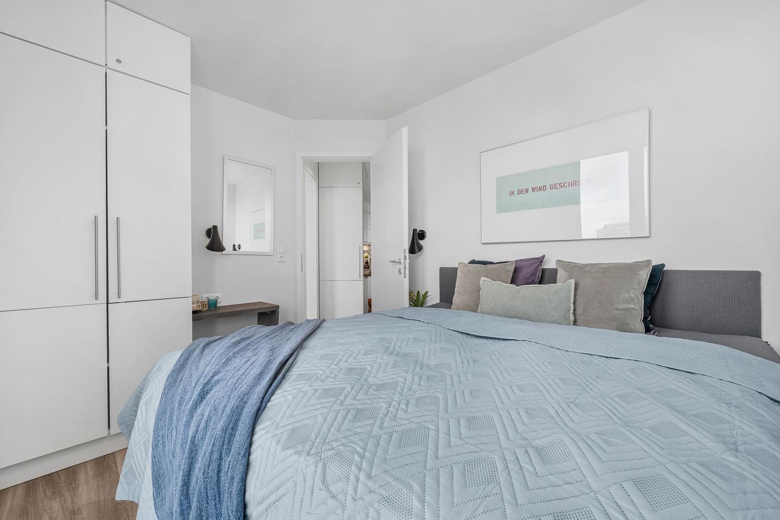 Schlafzimmer mit Bett, Kleiderschrank und Wandbild.