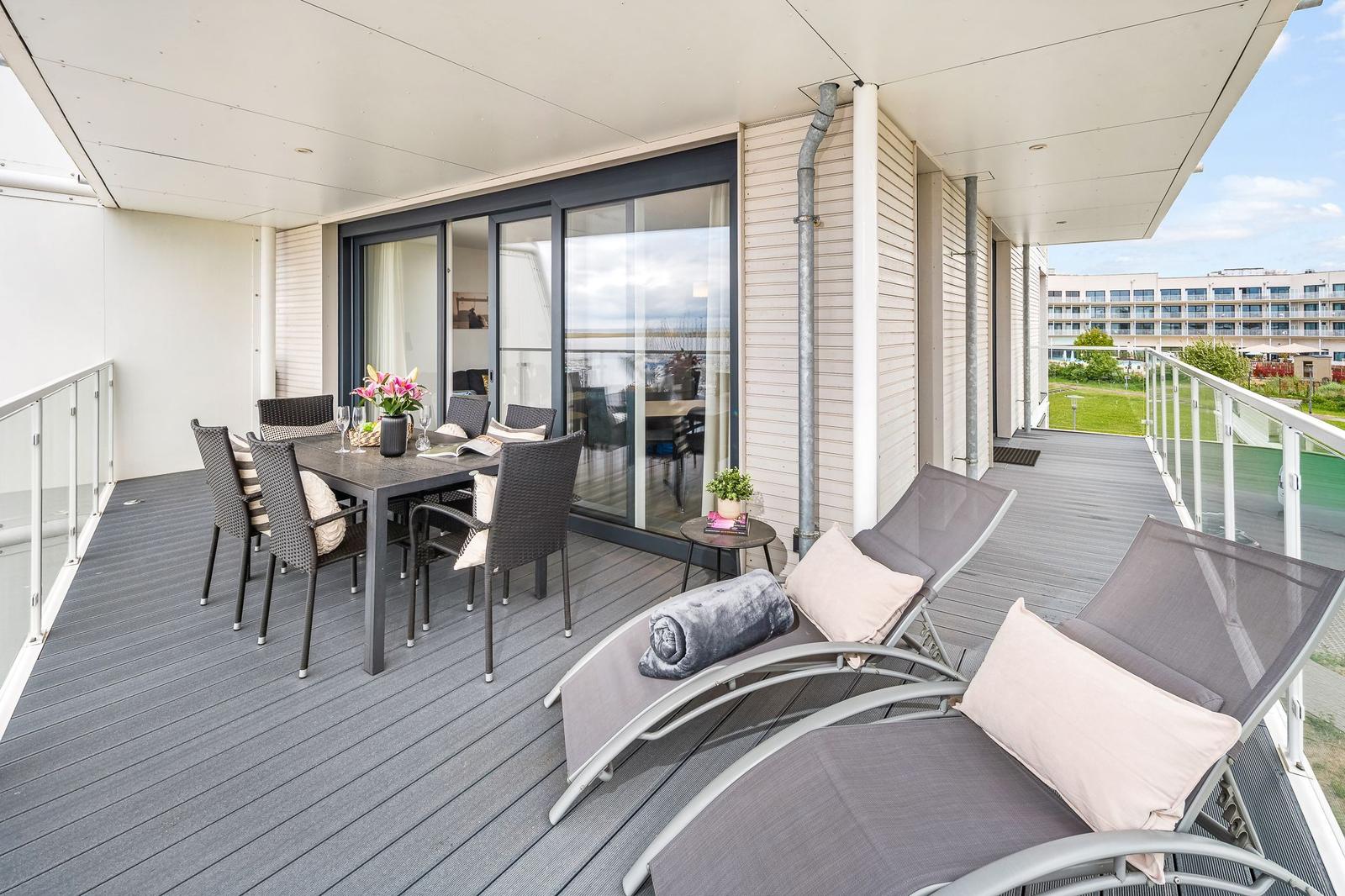 Terrasse mit Essgruppe und Liegestühlen. Blick auf Hotel und Grünfläche.