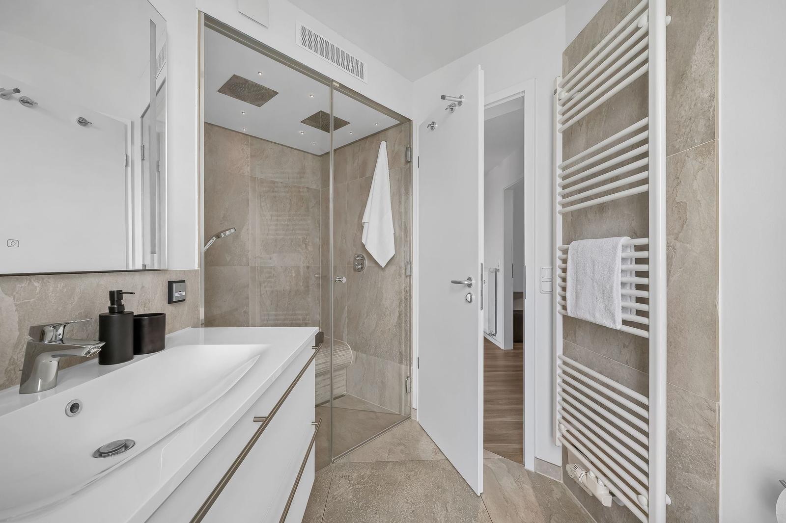 Badezimmer mit Dusche, Waschbecken und Handtuchhalter.