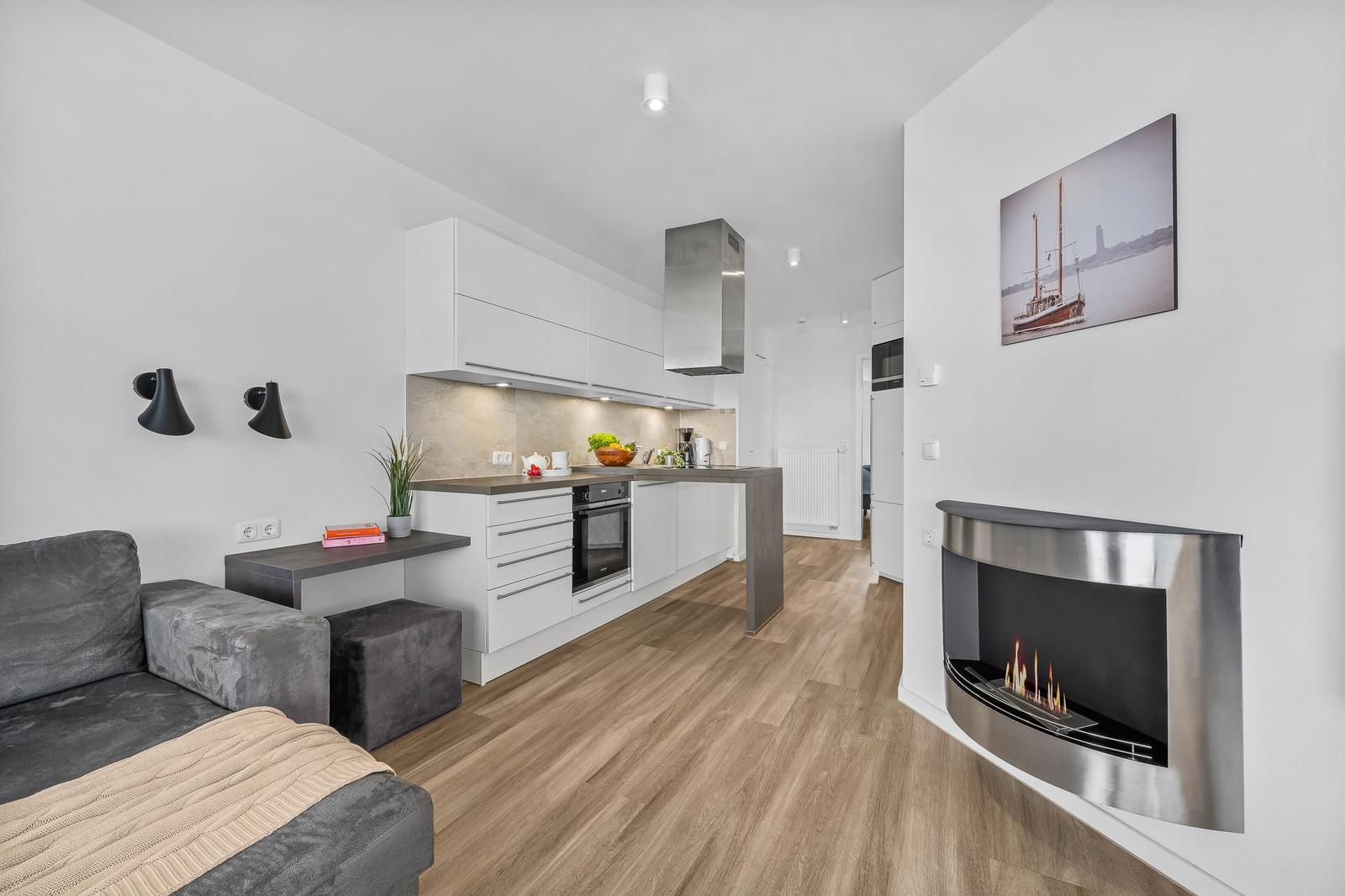 Wohnküche mit Kamin, Sofa und moderner Küchenzeile.