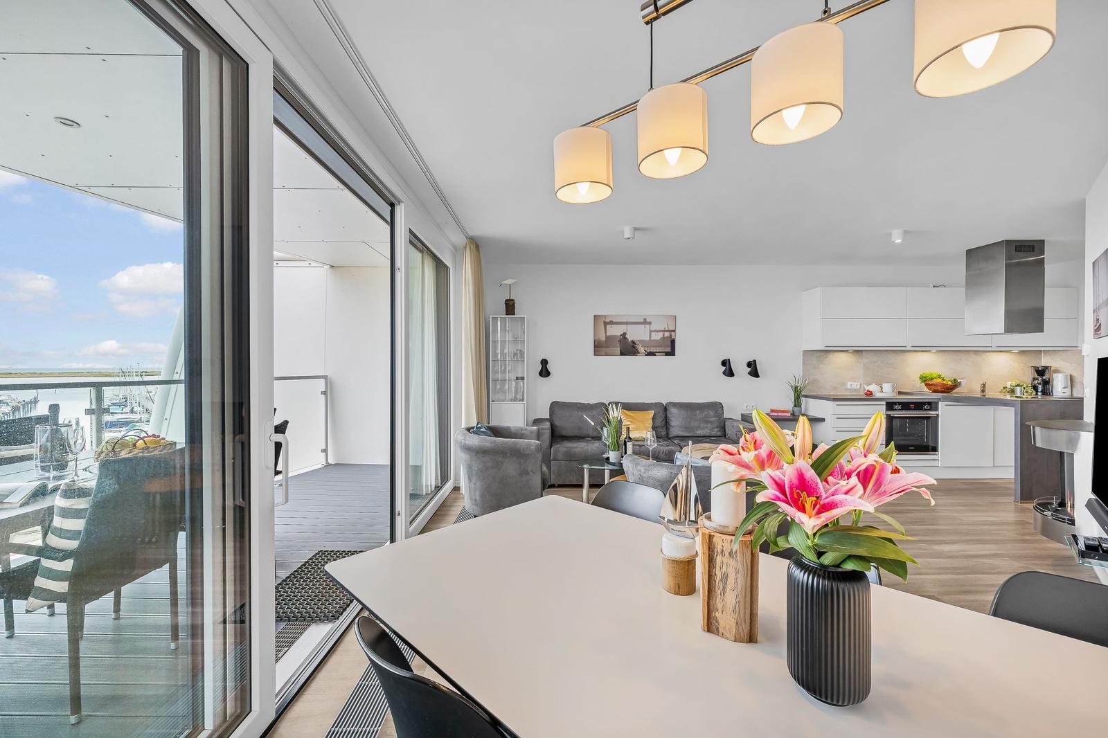Wohnung mit Blick auf Hafen, Küche und Essbereich mit Blumen auf Tisch.