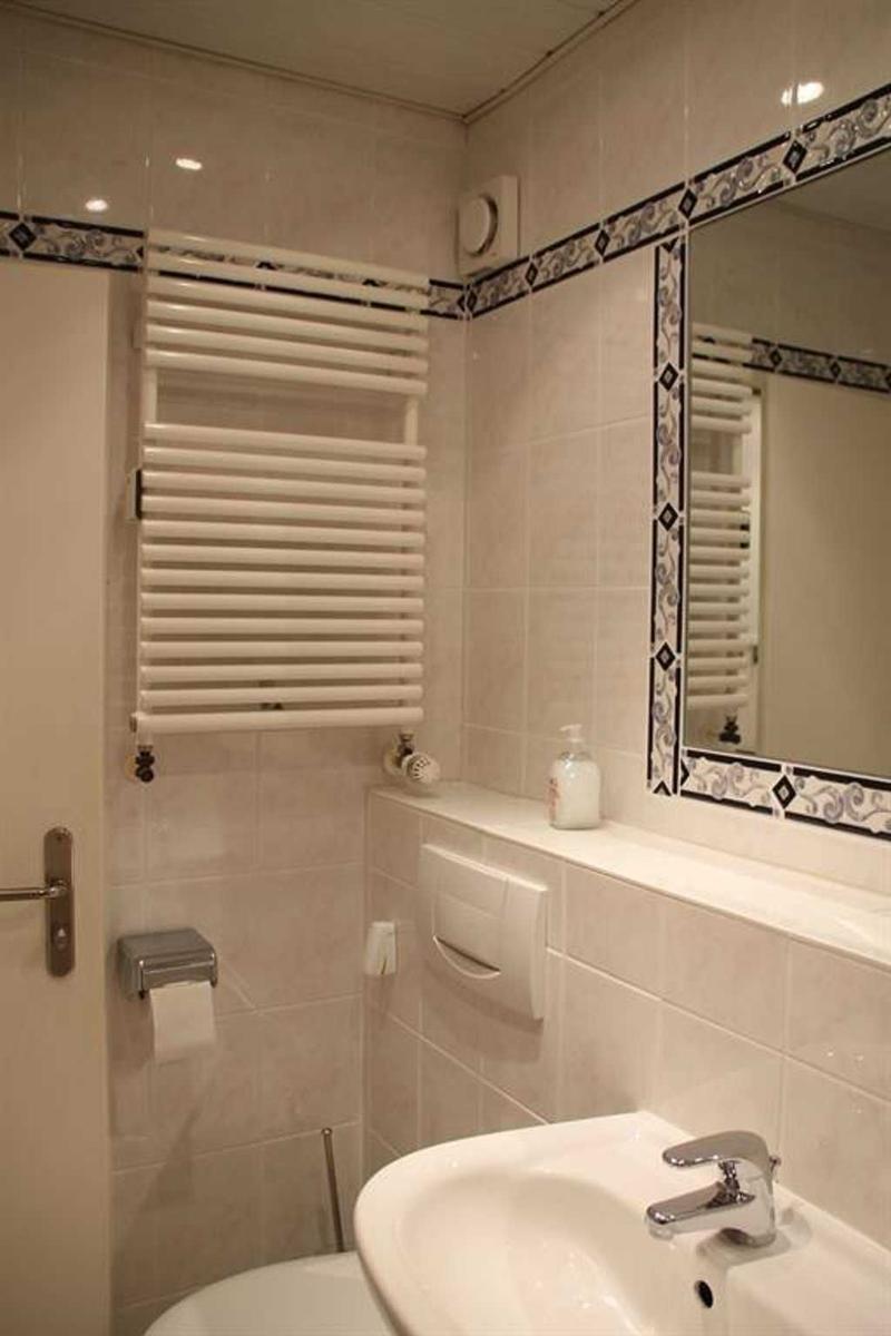 Bathroom with sink, mirror, towel radiator, and toilet paper holder.