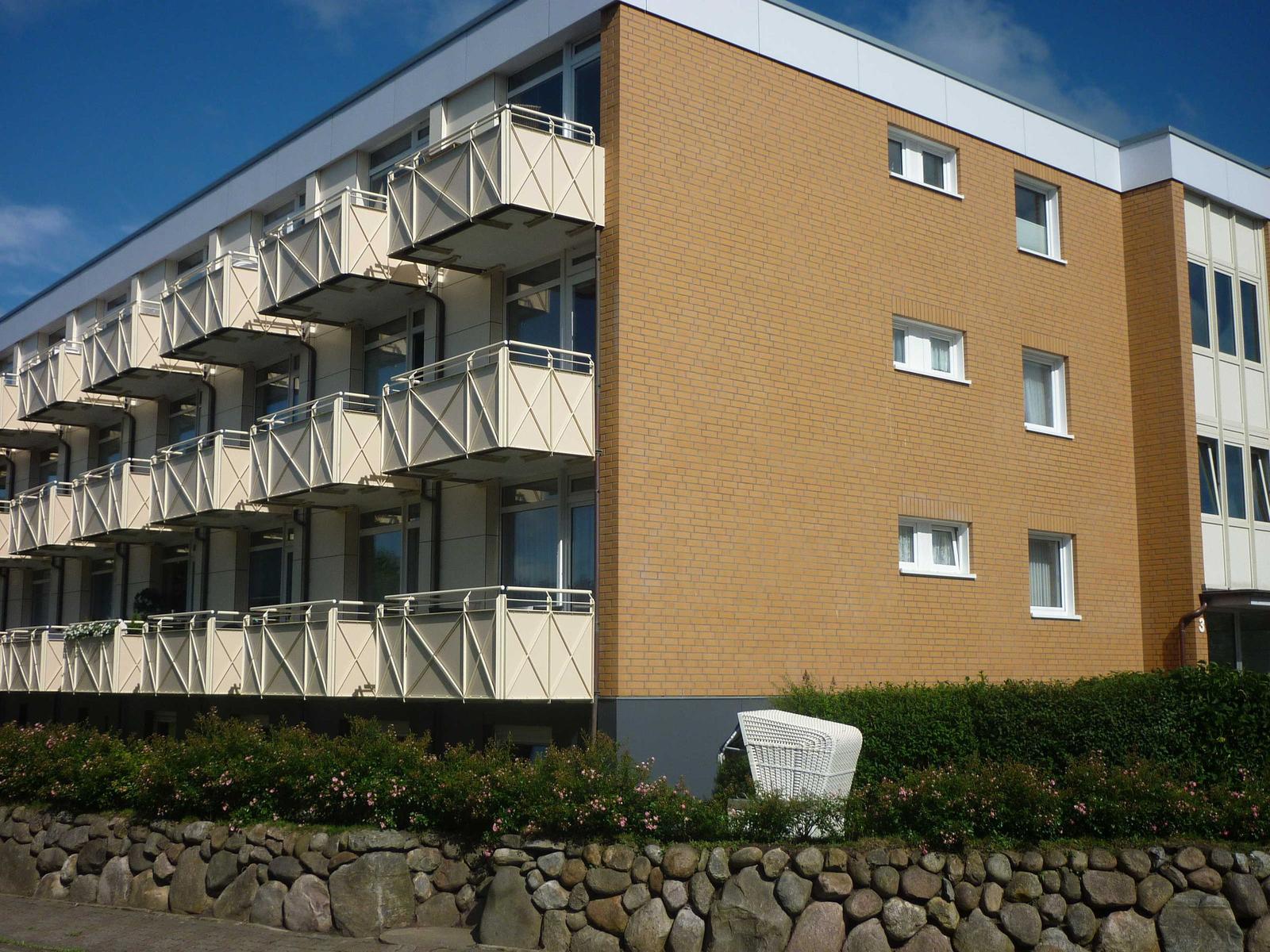 Modern apartment building with balconies and garden area.