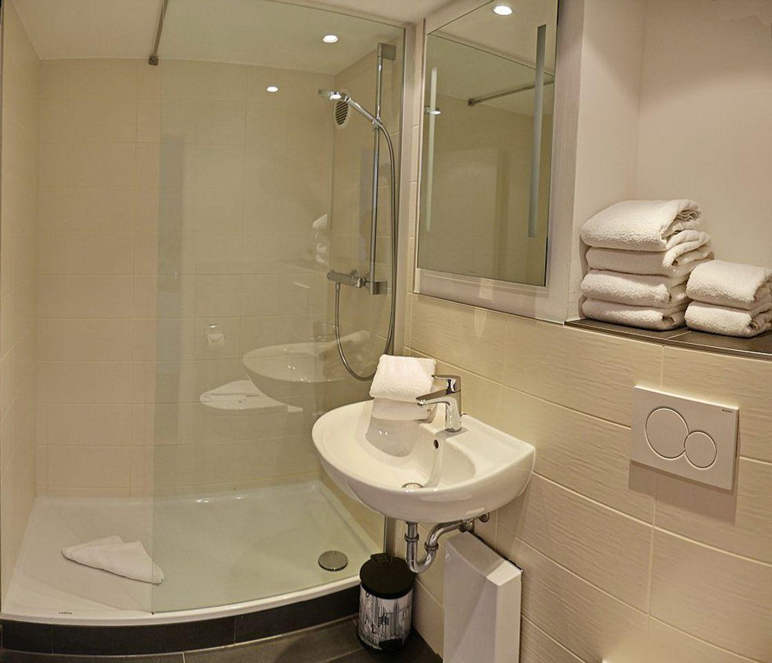 Badezimmer mit Dusche, Waschbecken und Handtüchern.
