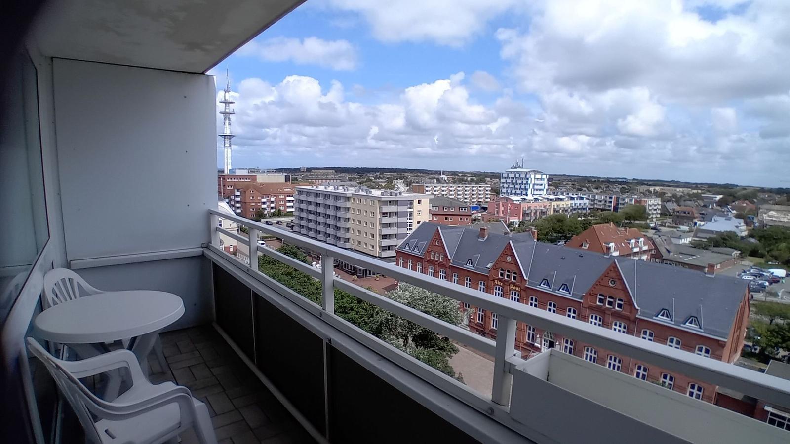 Balkon mit Tisch und Stühlen. Blick auf Stadt und Fernsehturm.