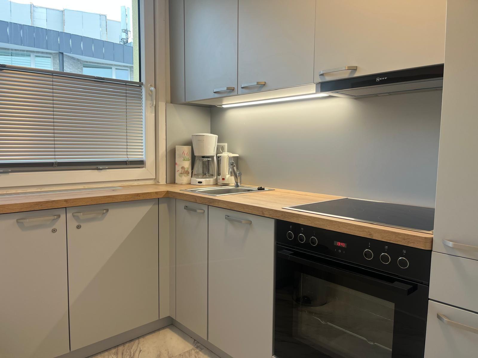 Kitchen with worktop, sink, coffee machine, and stove.
