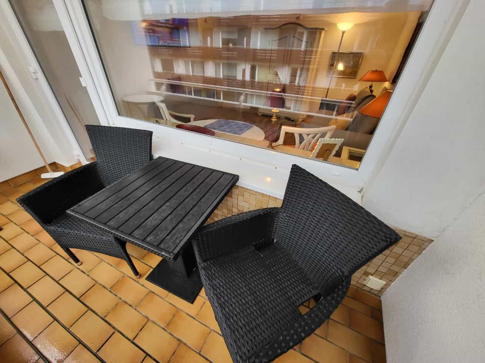 Terrace with table and two chairs, view into interior.
