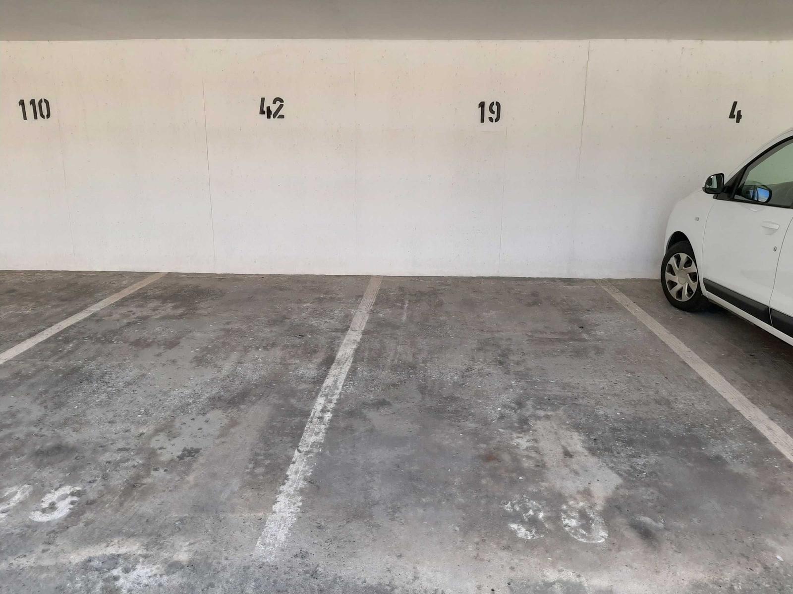 Parkplatz mit markierten Stellplätzen und einer weißen Fahrzeugseite.