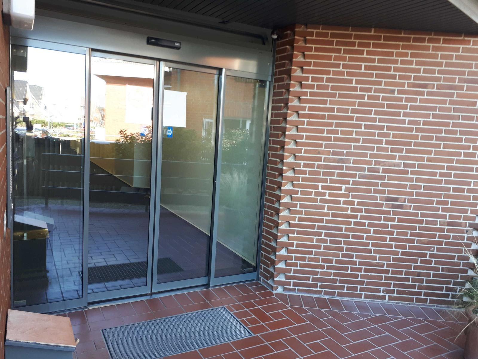 Entrance with automatic sliding doors and brick wall
