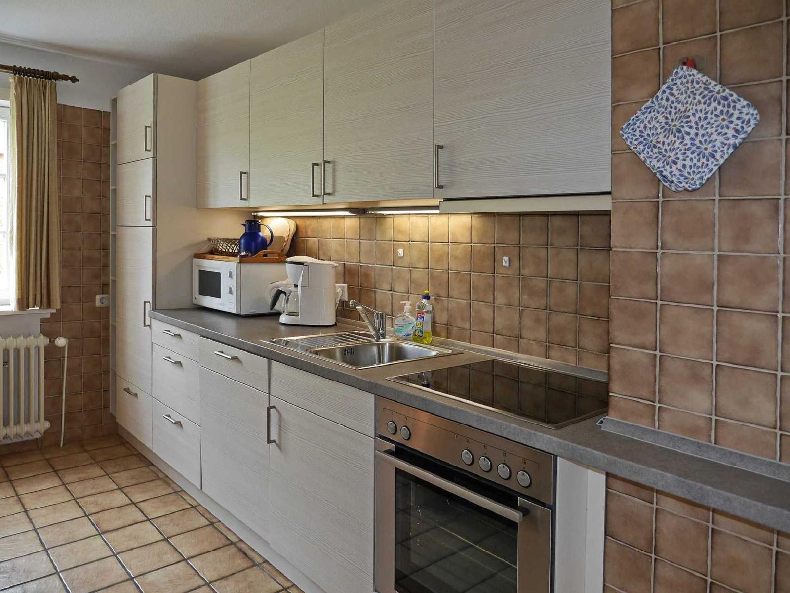 Kitchen with countertop, sink, stove, and microwave.