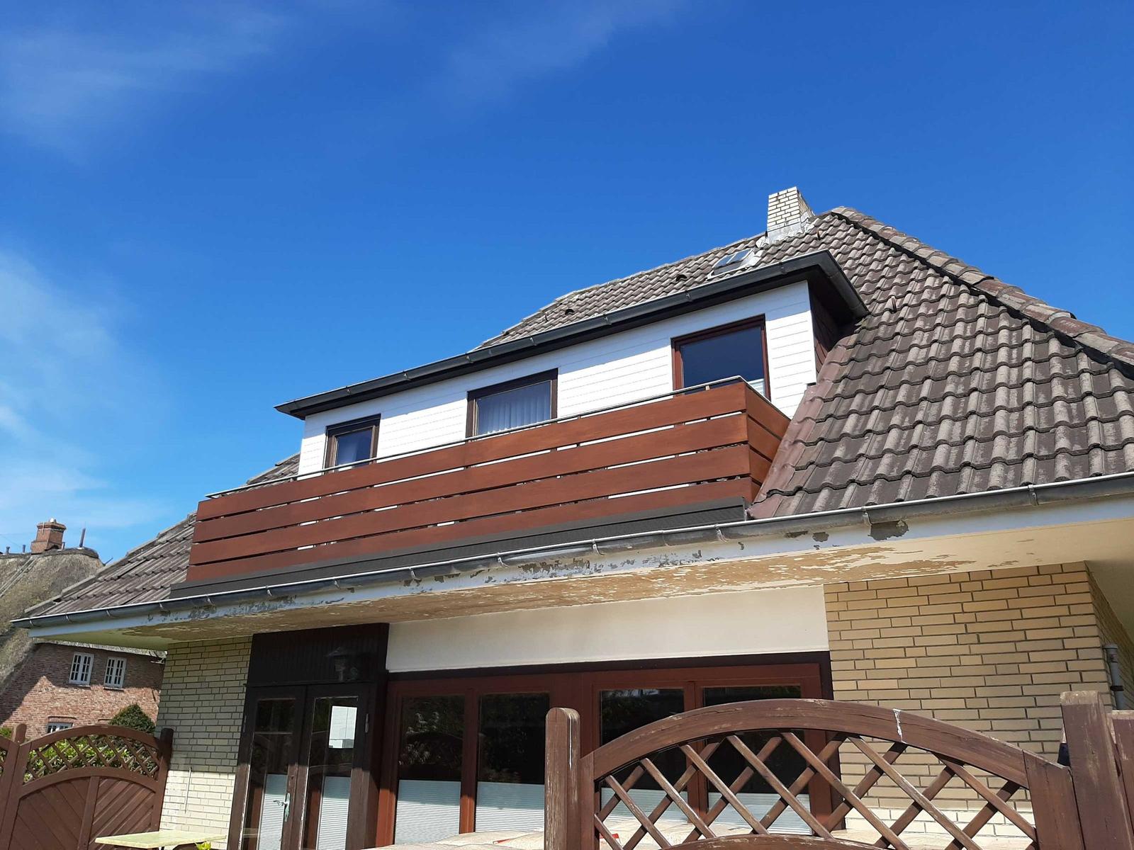House with balcony, roof, and terrace under blue sky