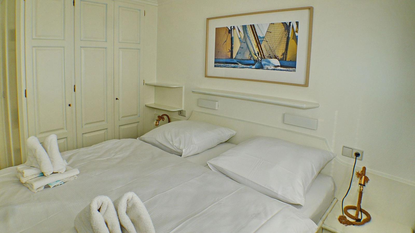 Bedroom with bed, wardrobe, and wall art featuring sailboats.
