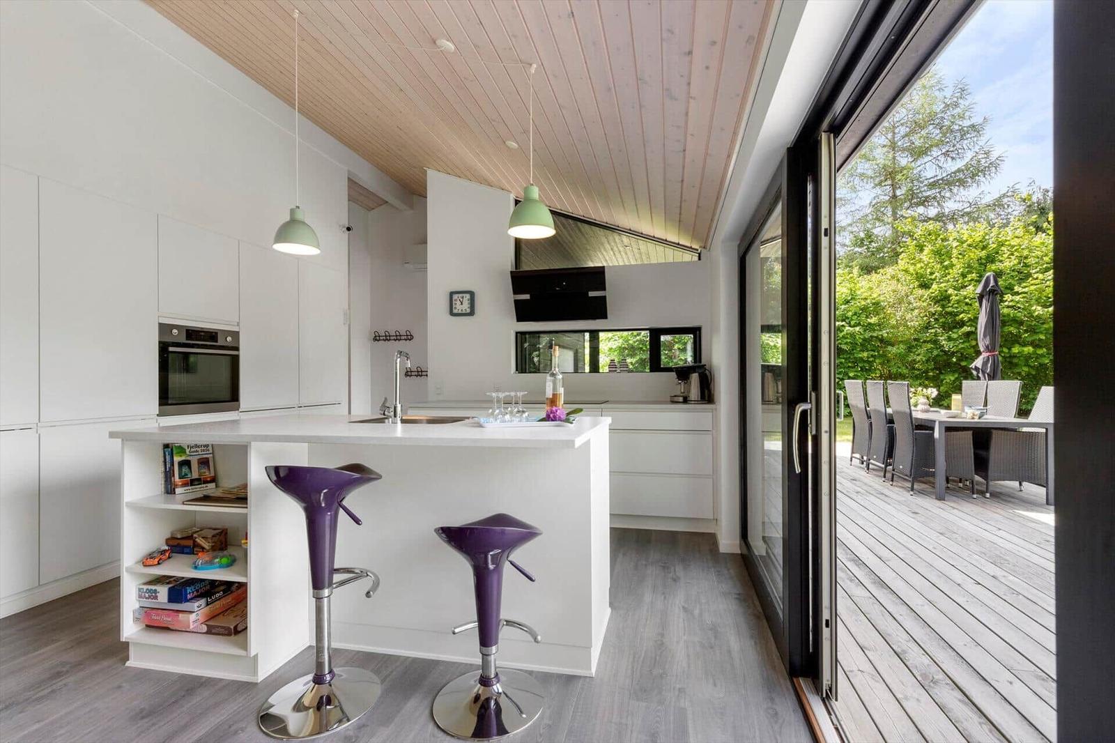 Moderne Küche mit Kücheninsel und Terrasse. Purpurfarbene Barhocker und Holzdecke.