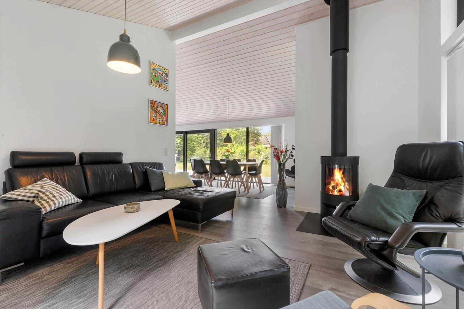 Wohnzimmer mit Sofa, Sessel und Kamin. Durchgang zur Essnische mit Tisch und Stühlen.
