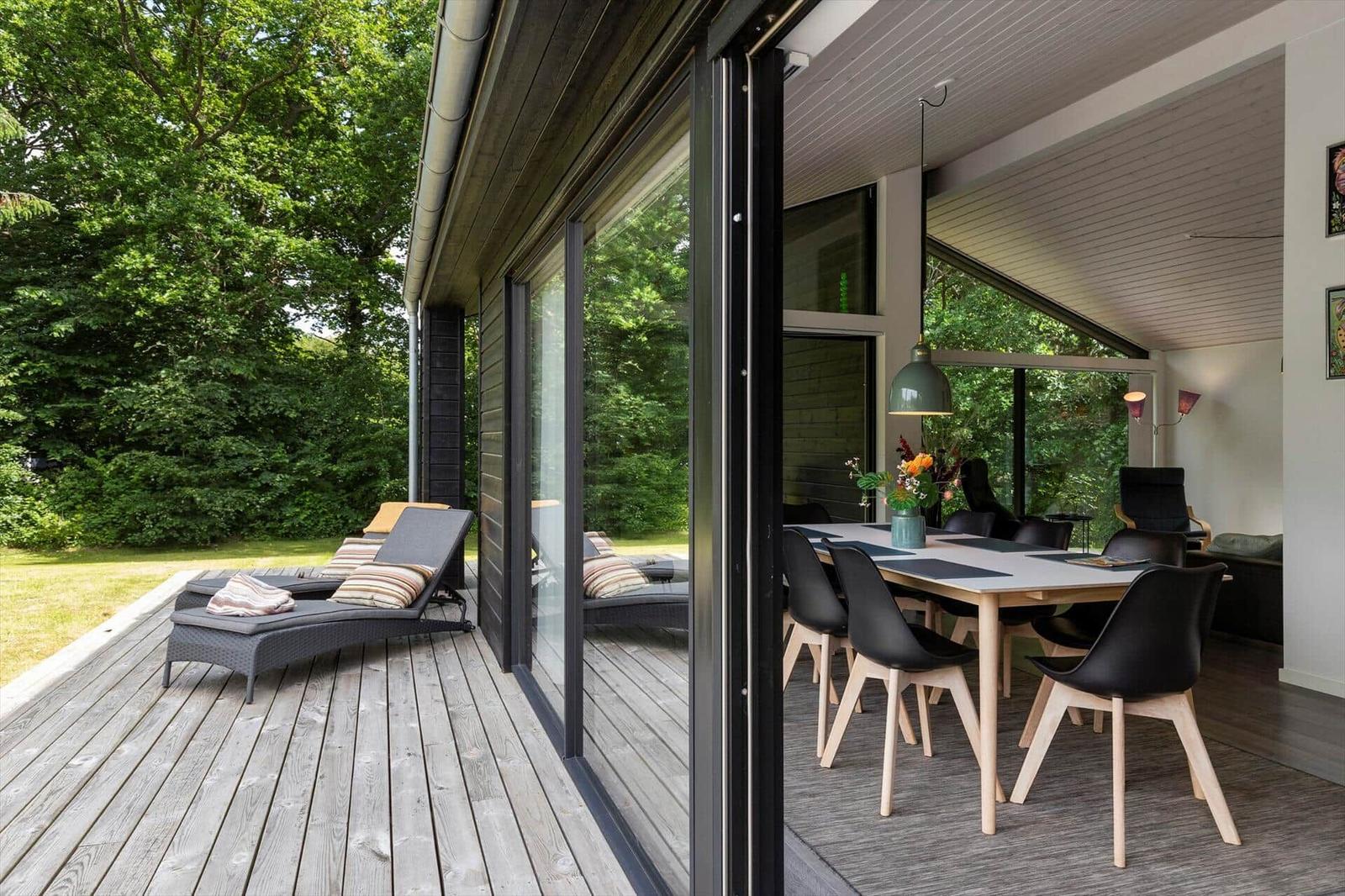 Terrasse mit Liegen und Blick in das Esszimmer mit Tisch und Stühlen.