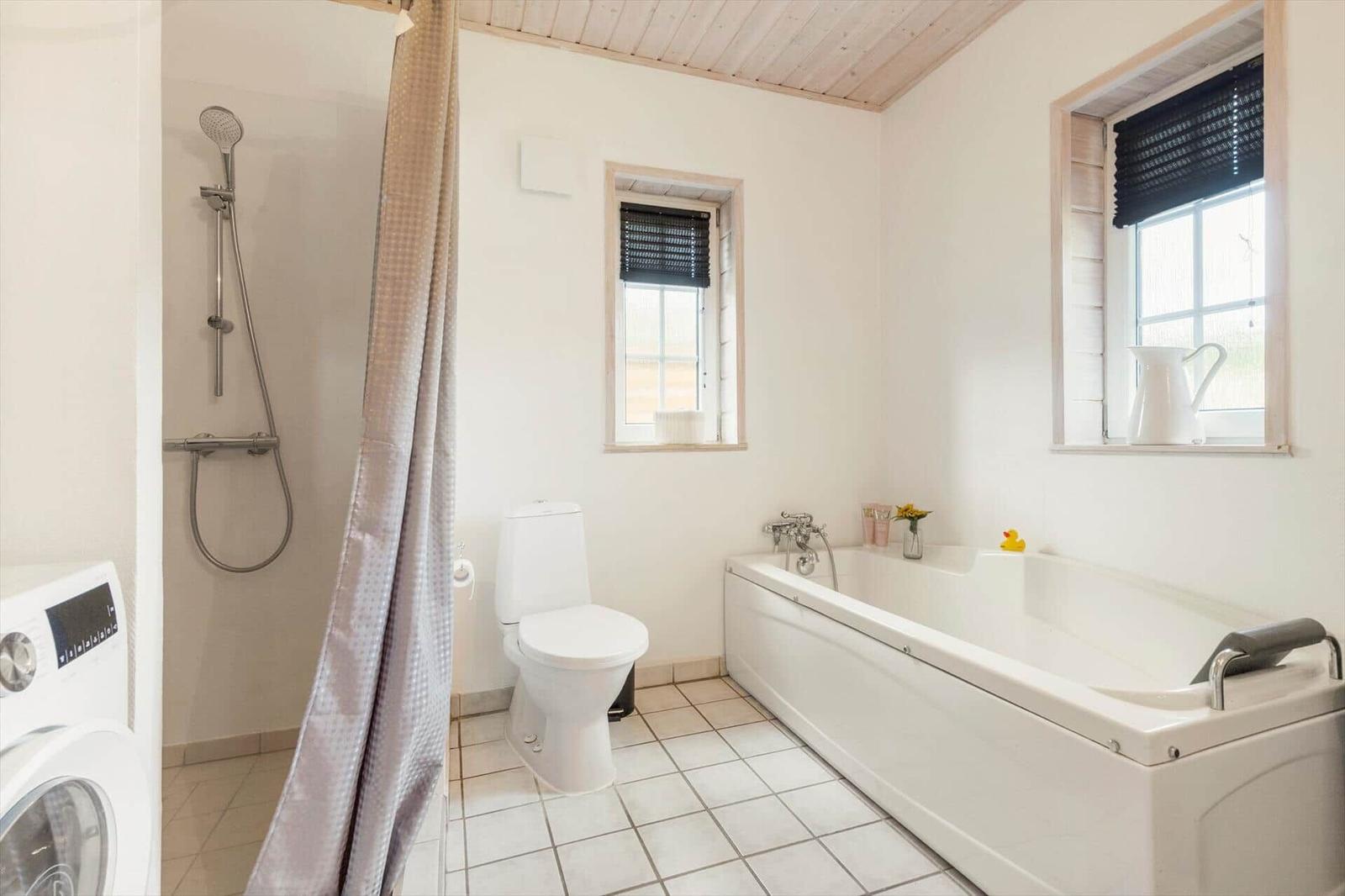Badezimmer mit Badewanne, Dusche, Toilette und Waschmaschine.