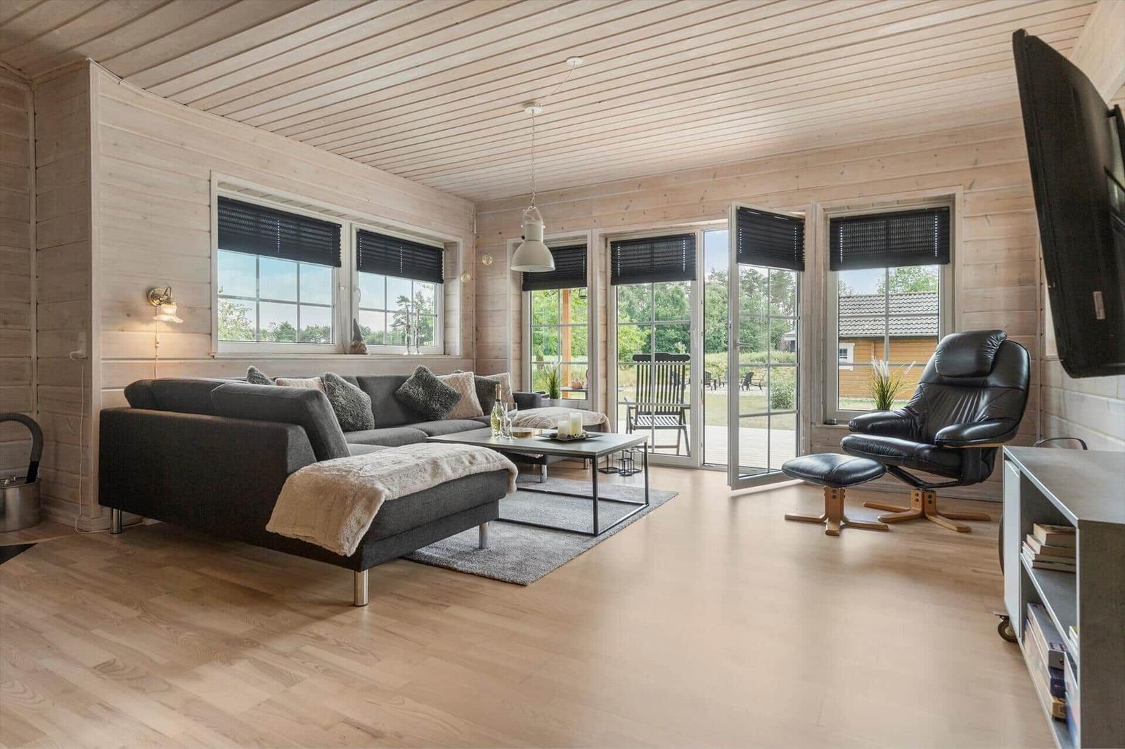Wohnzimmer mit Sofa, Sessel und Fenstern zur Terrasse.