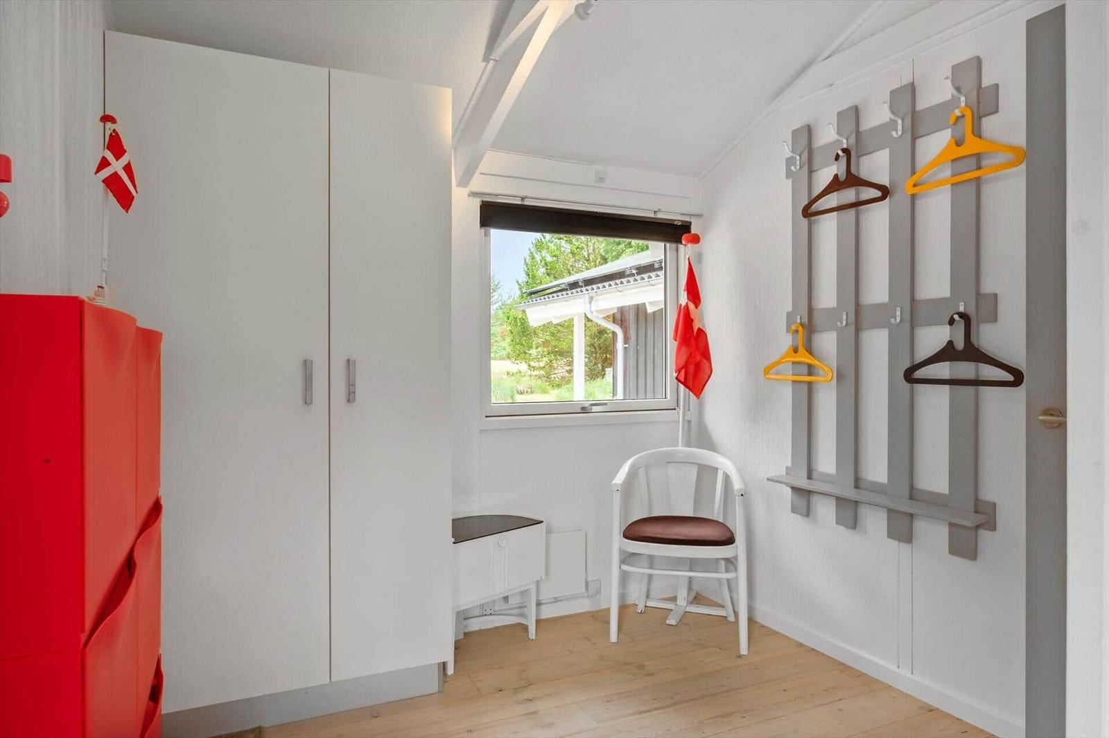 Schlafzimmer mit Kleiderschrank, Stuhl und Garderobe mit Haken.
