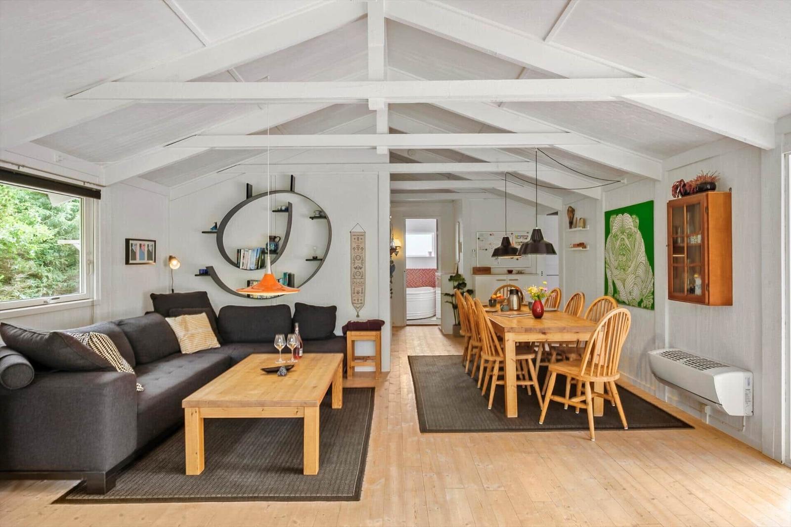 Wohn- und Essbereich mit Holzboden, Sofa, Esstisch und Blick in das Bad.
