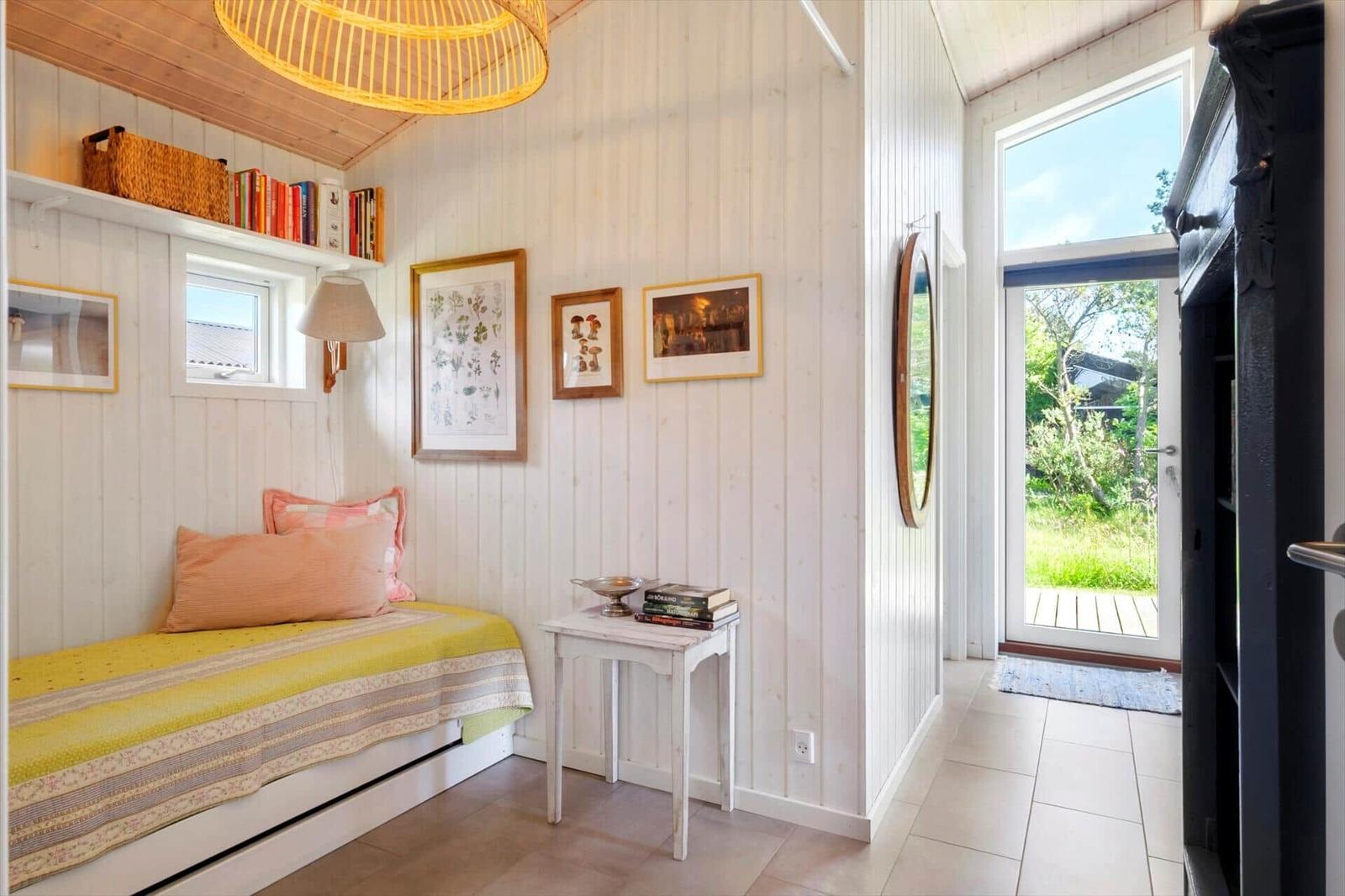 Ein Raum mit Bett, Wandregal und Tür zum Garten. Holzwände und Decke.