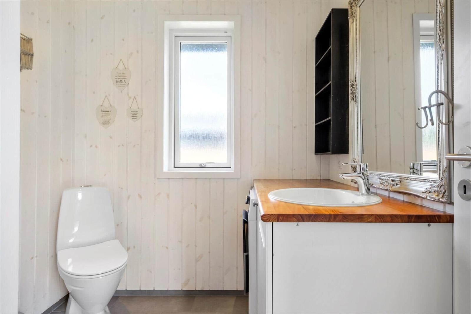 Badezimmer mit Toilette, Waschbecken und Fenster