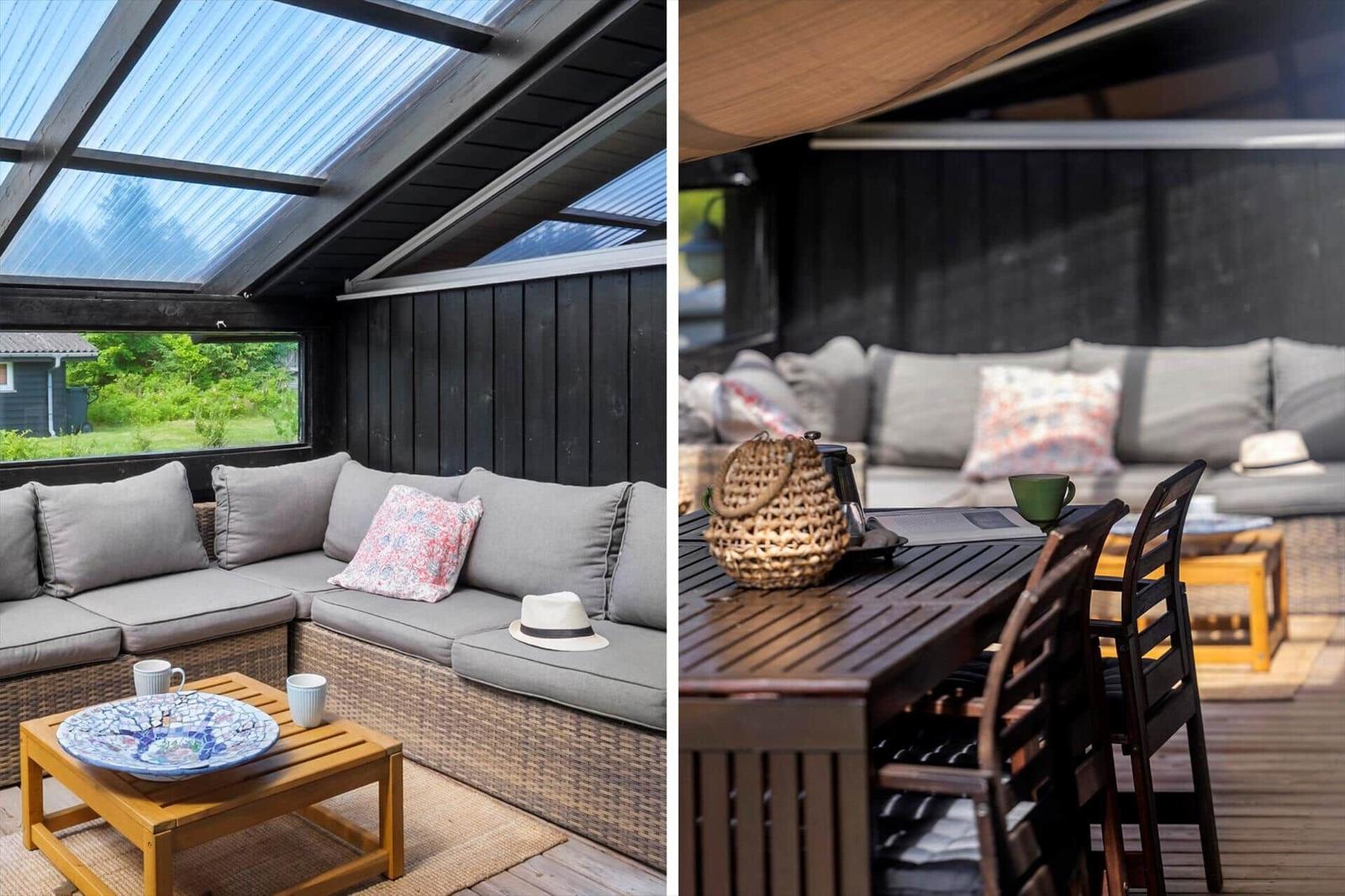 Terrasse mit Sitzgruppe, Tisch und Sonnenschutz. Glasdach und Holzwände.