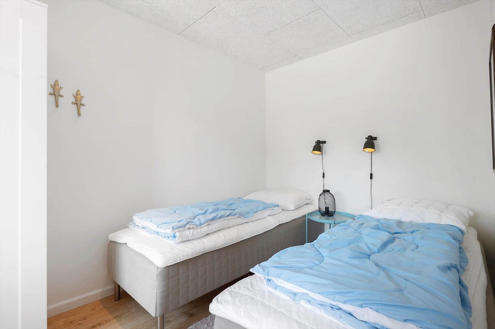 Zwei Betten mit blauen Bettdecken und Nachttisch mit Lampen.