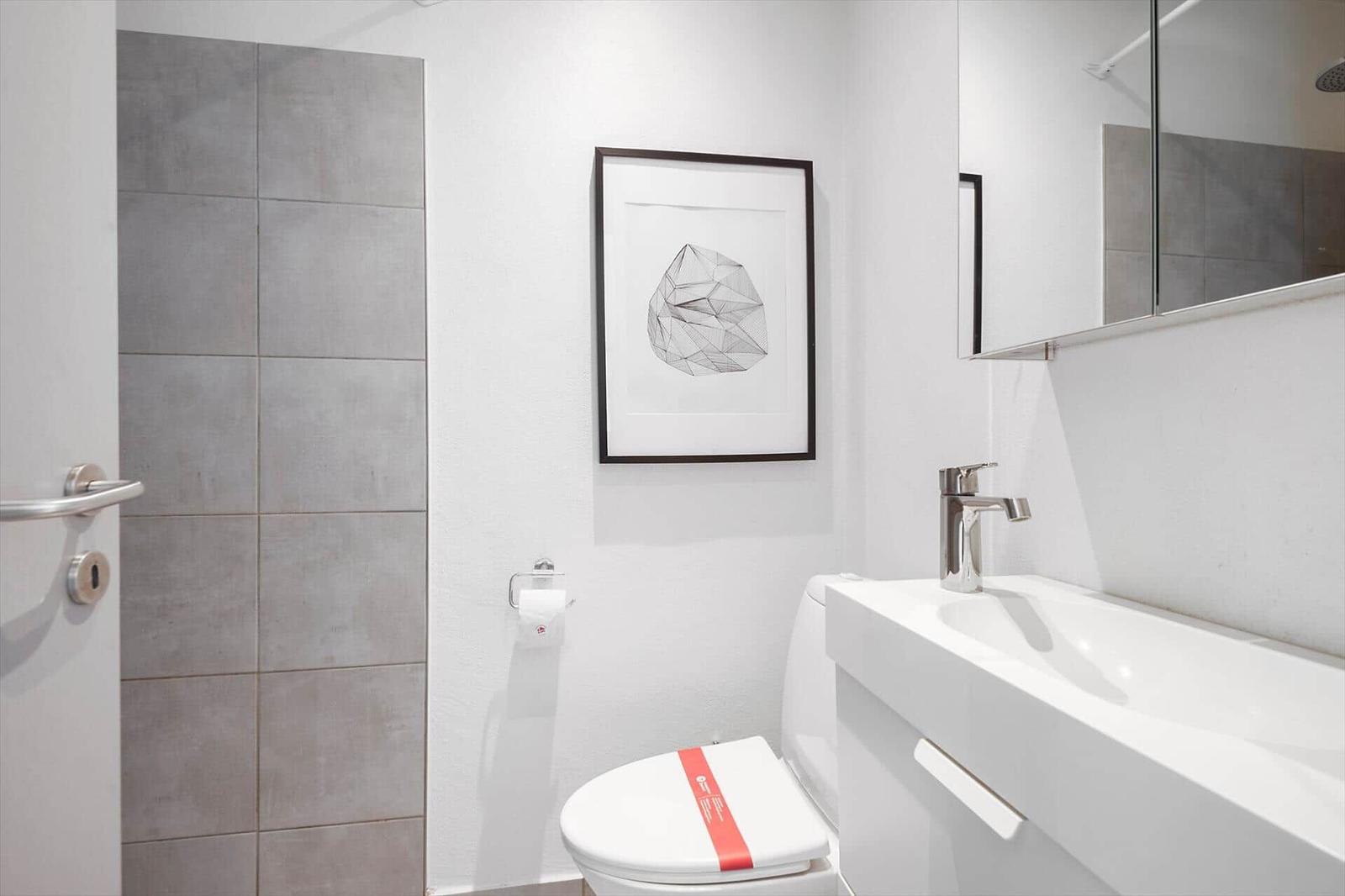 Badezimmer mit Toilette, Waschbecken und Dusche. Wandbild und Spiegel.