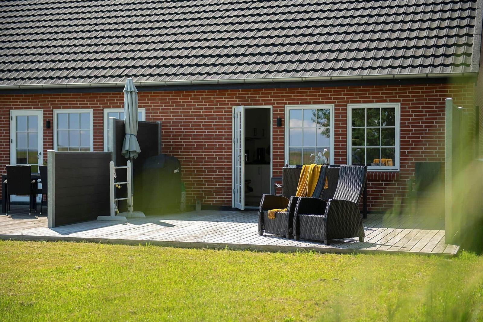 Roter Backsteinbau mit Terrasse, Garten und Sitzgelegenheiten.
