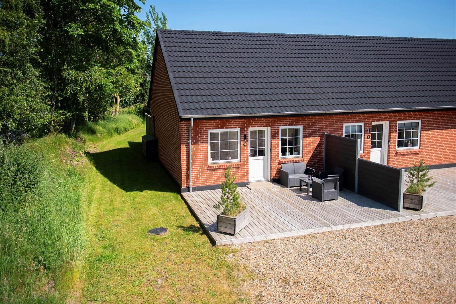 Rotes Backsteinhaus mit Terrasse und Garten. Außenbereich mit Sitzmöbeln und Pflanzen.