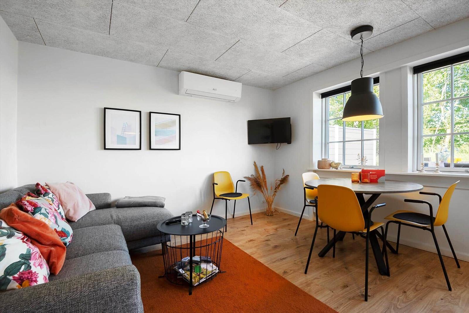 Wohn- und Essbereich mit Sofa, Esstisch und Fenstern.