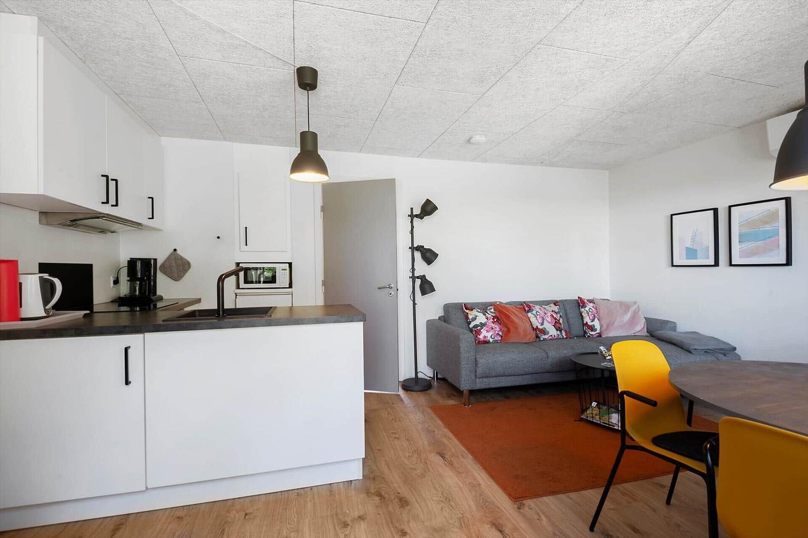 Wohnung mit Küche, Wohnbereich und Essplatz. Ein Sofa, zwei Stühle und eine Kücheninsel.